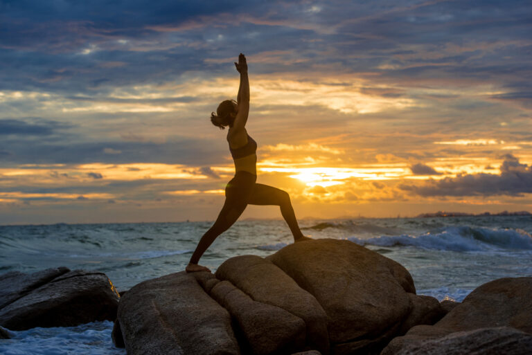 Silhouette,Young,Woman,Practicing,Yoga,On,A,Rock,At,The
